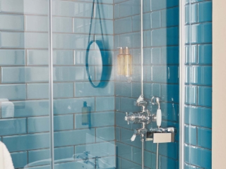A chrome rain shower in a cubicle of blue tiles in a Deluxe Room in Brambles hotel in Inveraray in Scotland