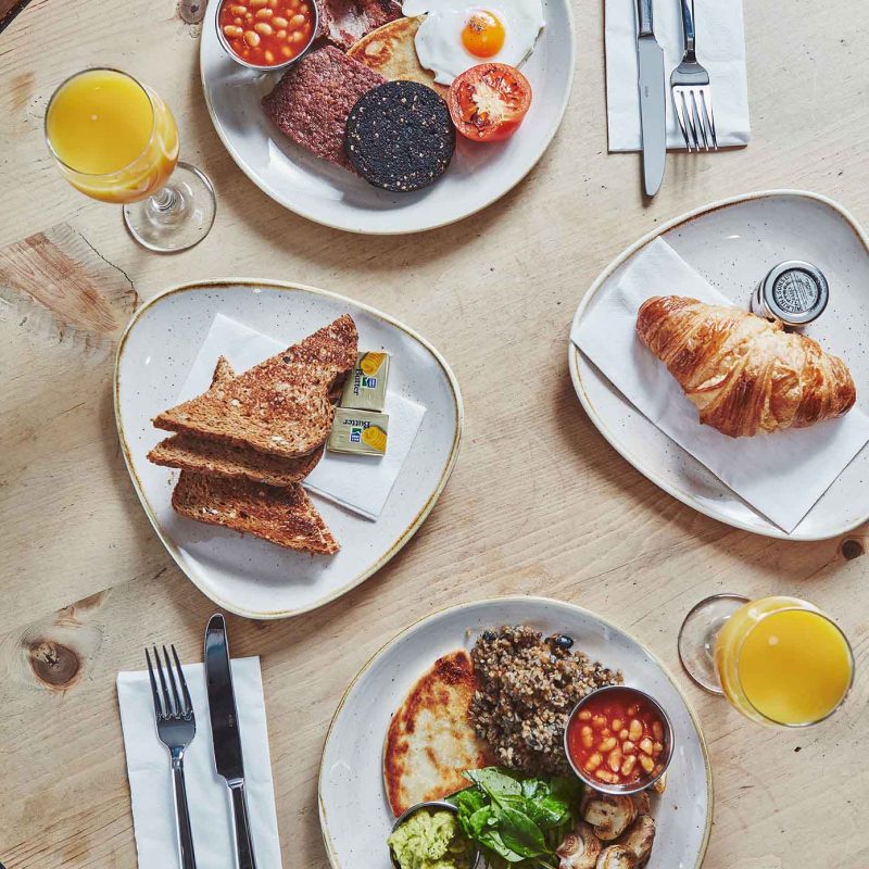 A Scottish breakfast with fresh orange juice on a table set for dining in Brambles of Inveraray Hotel restaurant.