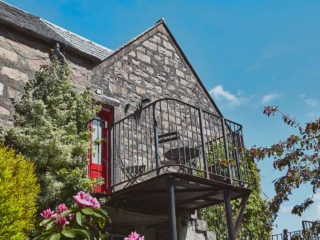 The balcony overlooking the stunning and lush courtyard at Lochview Apartment part of Brambles hotel in Inveraray in Scotland
