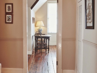 The hallway with a gorgeous old wooden floor leading into a room with an antique table and chairs at Lochview Apartment part of Brambles hotel in Inveraray in Scotland