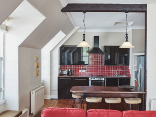 The kitchen in the open plan living area with an old wooden ceiling beam and antique lights hanging from it at Lochview Apartment part of Brambles hotel in Inveraray in Scotland