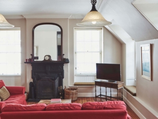 The living room with a stunning antique fireplace and eaved ceilings at Lochview Apartment part of Brambles hotel in Inveraray in Scotland