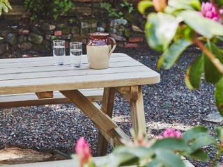The picnic table in the courtyard with a jug and two glasses of water with rhododendrons in bloom at Lochview Apartment part of Brambles hotel in Inveraray in Scotland