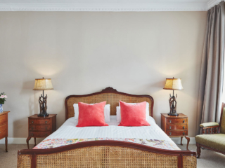 An antique rattan double bed with antler bedside lights in a Superior Room in Brambles hotel in Inveraray in Scotland