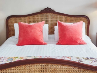An antique rattan double bed with antler bedside lights in a Superior Room in Brambles hotel in Inveraray in Scotland