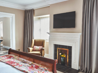 A beautiful double bedroom with antique furniture an old fireplace and bathroom off it with a roll top bath in it in a Superior Room in Brambles hotel in Inveraray in Scotland